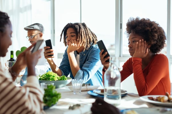Mensen aan lunchtafel kijkend op smartphone